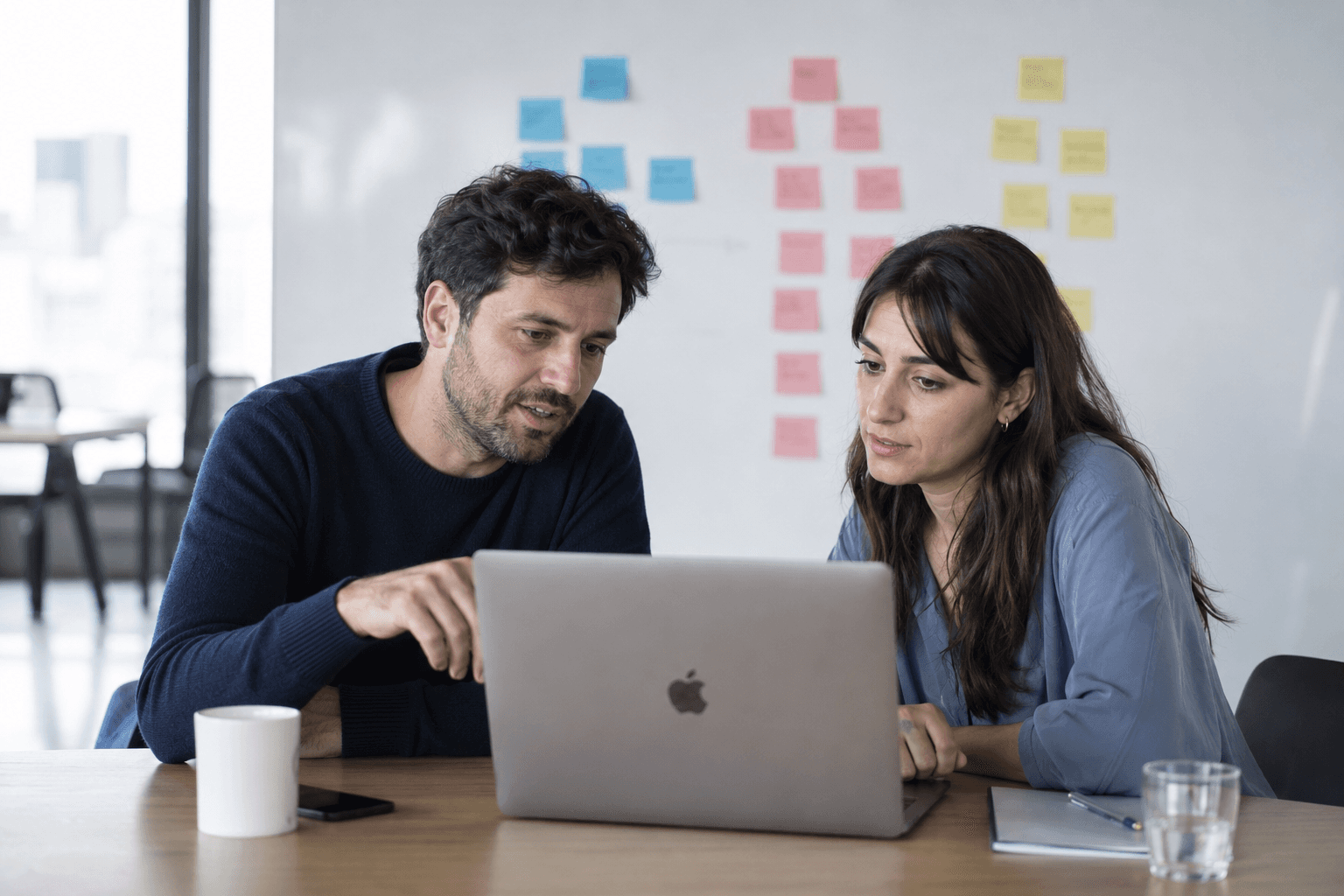 Two colleagues reviewing work together on a laptop