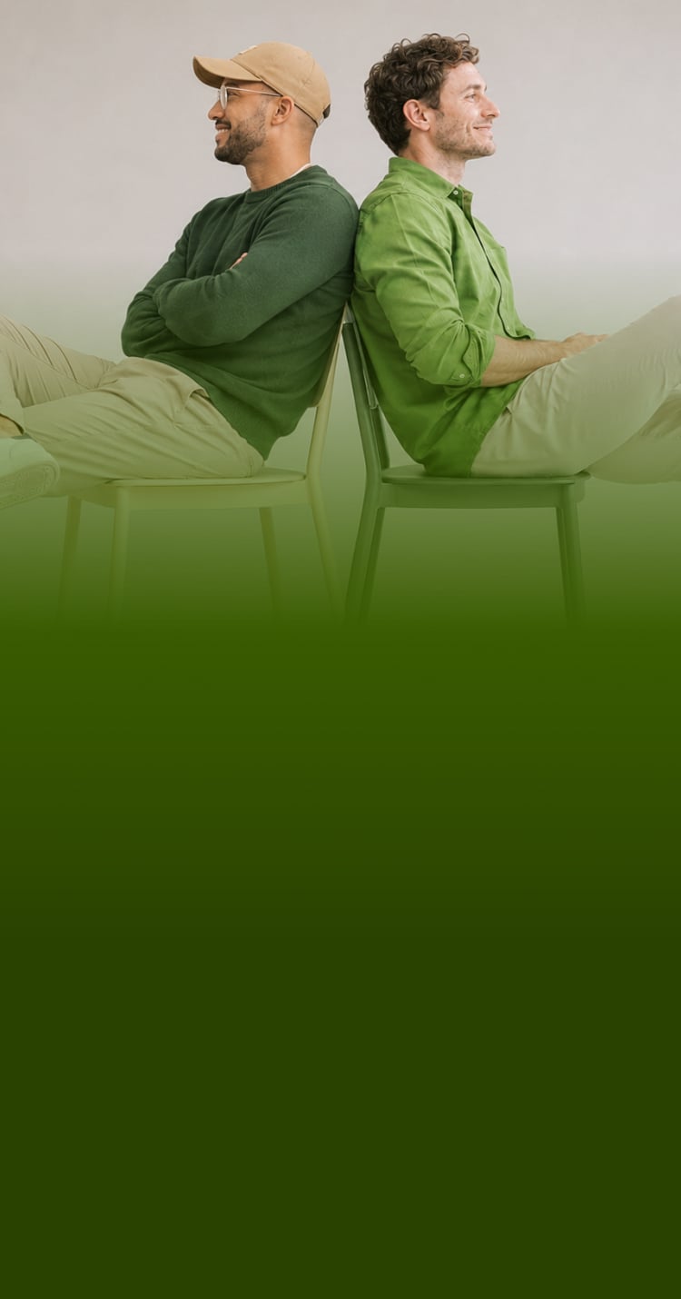 Two men laughing while sitting back-to-back on chairs