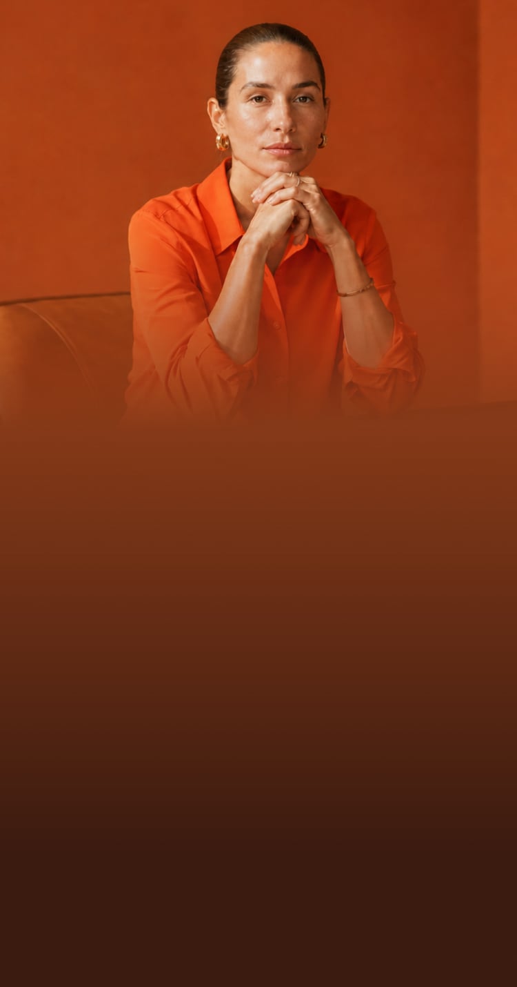 Woman in an orange suit working on a laptop